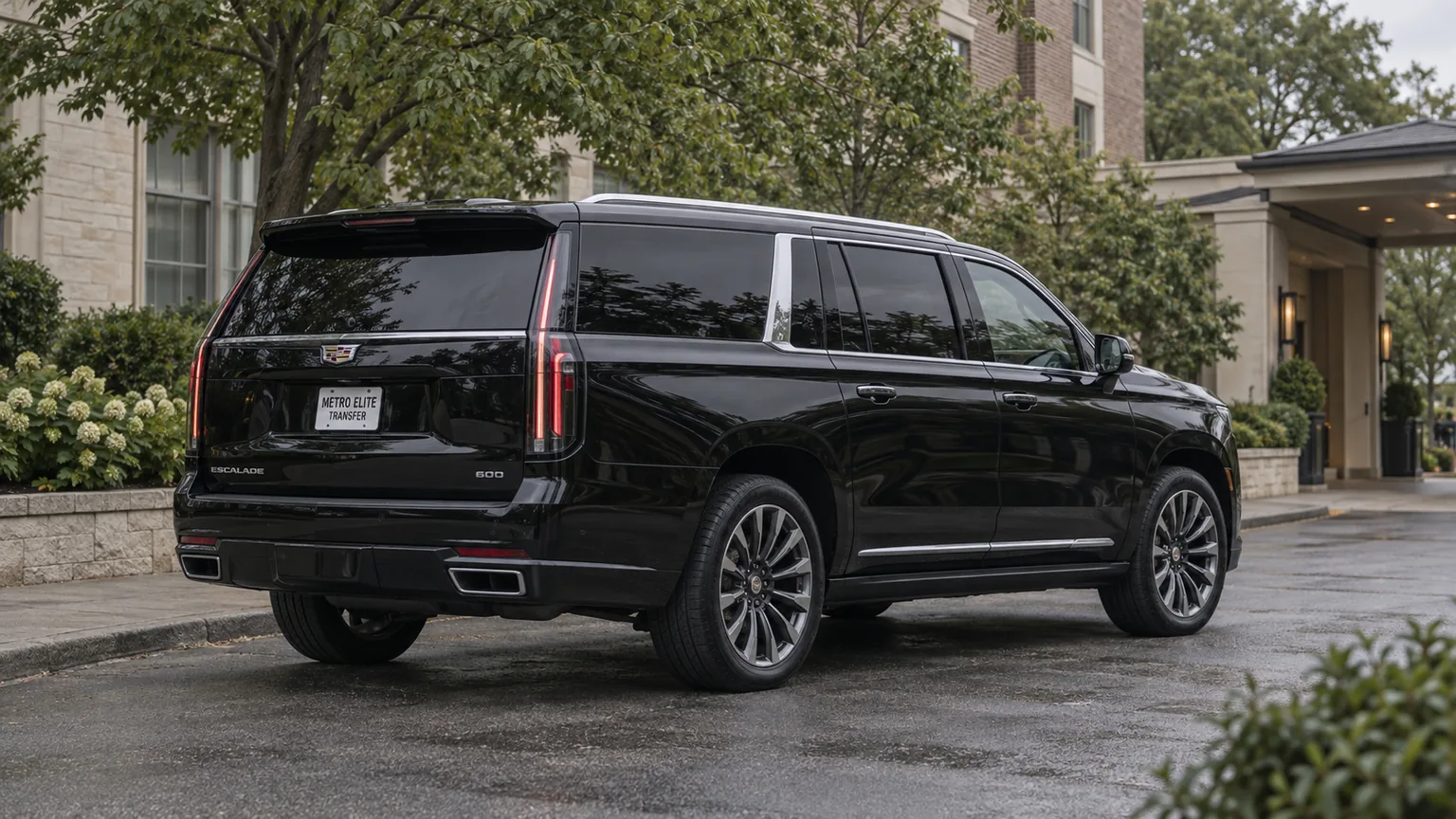 A black Cadillac Escalade ESV with a Metro Elite Transfer plate in a leafy hotel setting