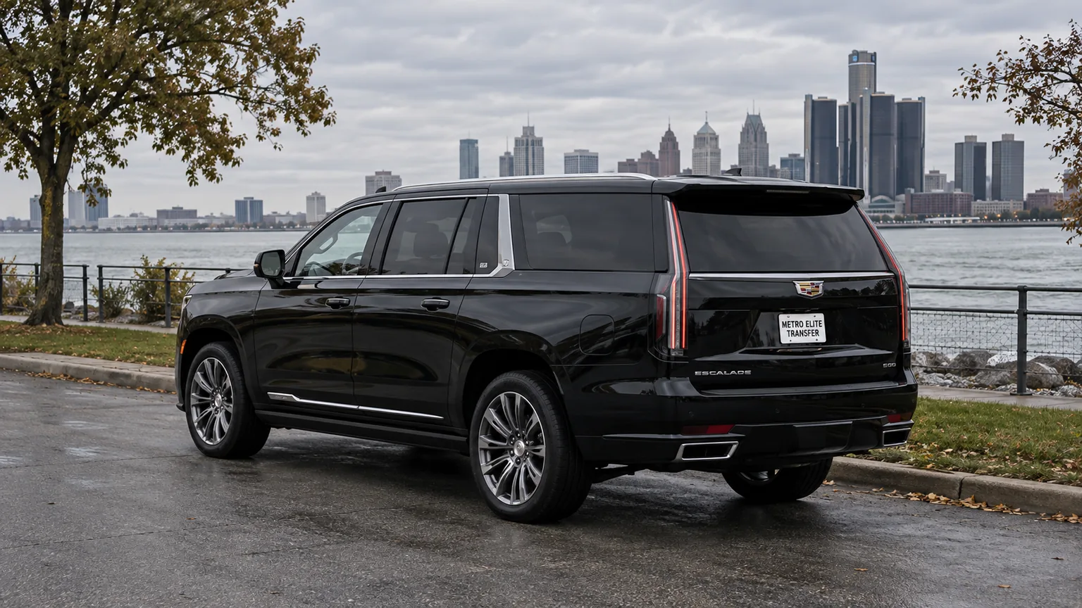 A black Cadillac Escalade ESV with a Metro Elite Transfer plate in a riverfront setting with a distant city skyline
